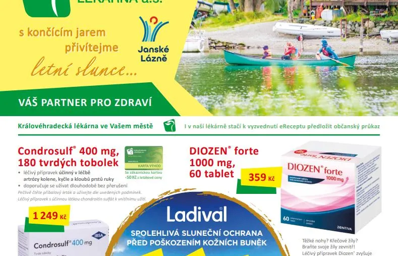 Rodina na zelené kanoi pádluje po jezeře u chaty s dřevěnou terasou, v pozadí loďky a stany v kempu